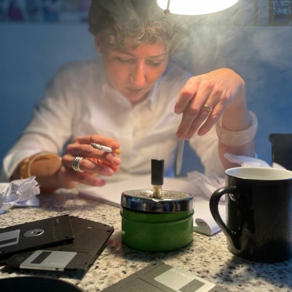 Frau mit zigarette rauchend mit floppy disks aus den 80er jahren trinkt kaffee und aschenbecher